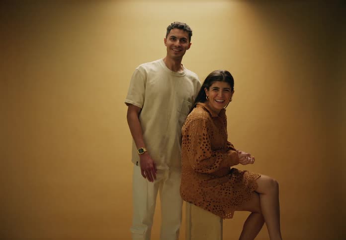 Man next to a pregnant woman both smile posing in a studio