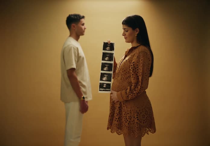 Woman holds ultrasound pictures in front of her partner