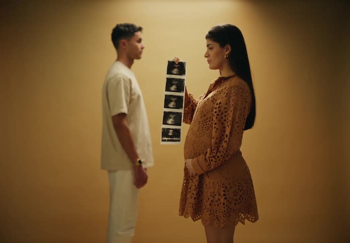 A woman is holding an ultrasound picture near a man