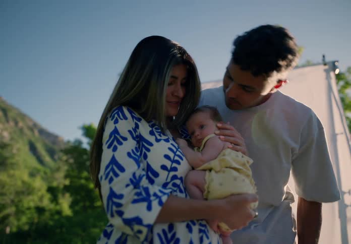 Mother holding newborn baby in her arms and father giving kisses