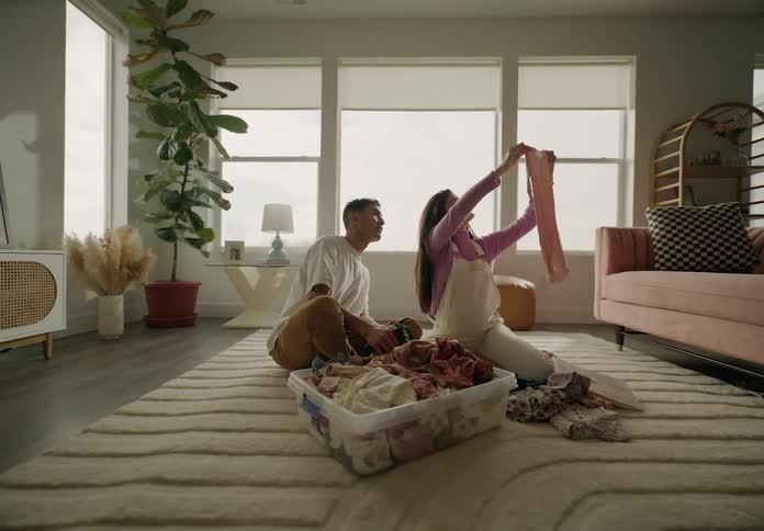 Man and woman sitting in living room looking at baby clothes