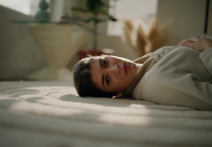 The face of a woman who is lying on the carpet of a living room and she is breathing in