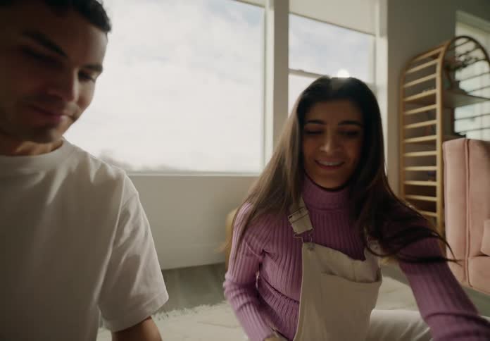 Woman and man sitting in living room looking at baby clothes during daytime