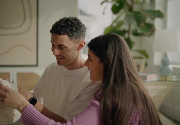 Happy couple looking at baby clothes in the living room