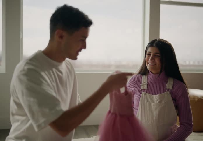 Happy man and woman looking at a pink childs dress