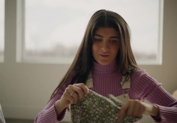 Woman looking at baby clothes next to a man