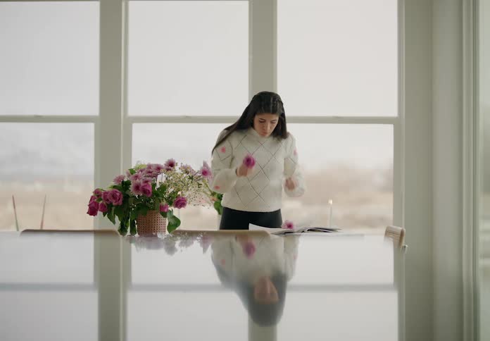 A woman pulls flowers from an arrangement and sets them on paper sitting on a table