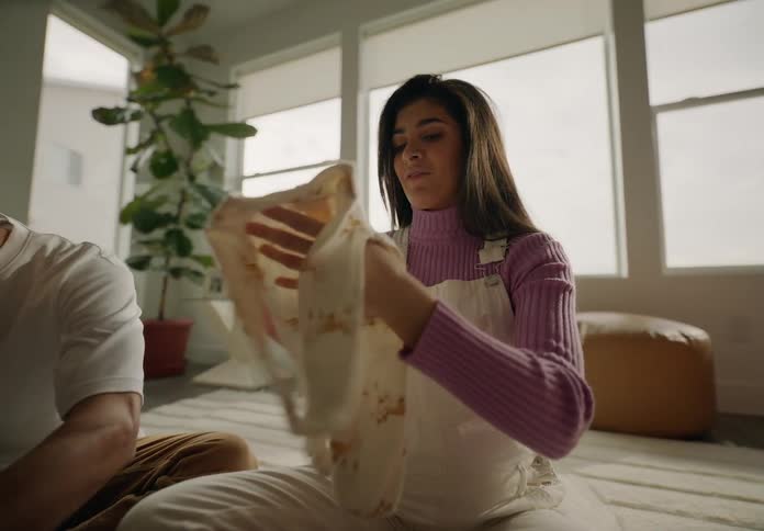 Couple sitting on living room rug looking at baby clothes