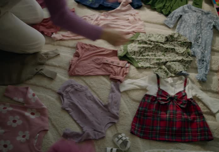 A couple arranging baby clothes over a rug in the livingroom