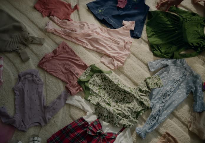 Two people sitting on a rug organizing a babys clothes
