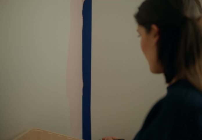 Woman with a paintbrush painting the white wall of a room