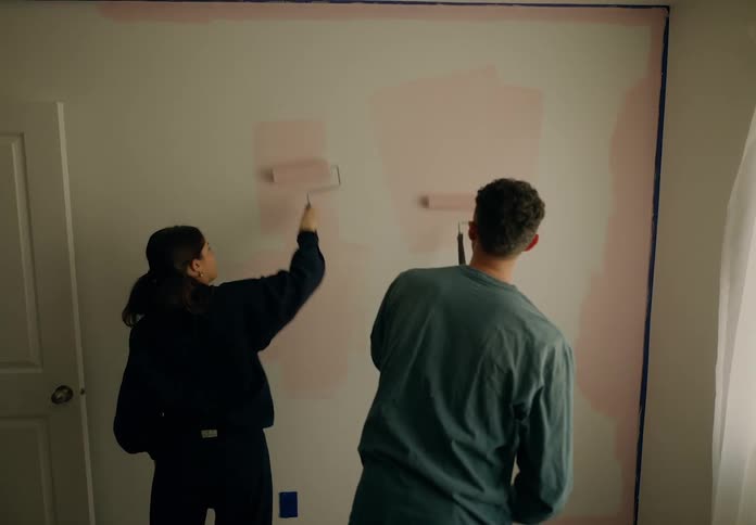 A man and woman are painting the wall