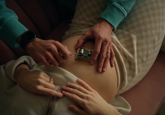 A hand playing a music box on a pregnant womans belly