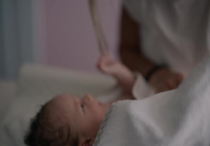 Mother smiles while using a towel to dry off her baby