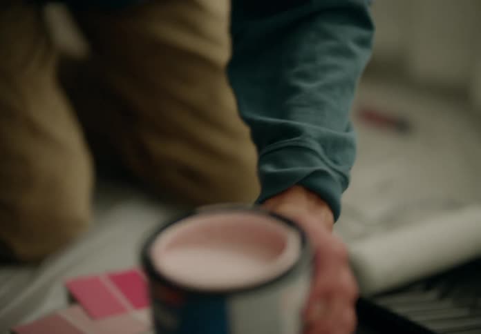 Hand holding a brush with light pink paint