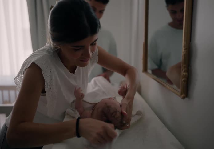 A mother is cleaning her baby in front of a mirror in the babys bedroom at home