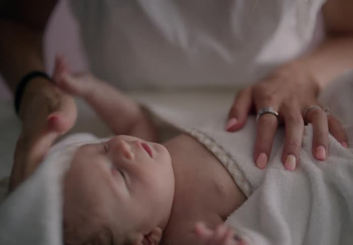 A mother drying her newborn son with a blanket after a bath
