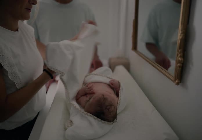 Father and mother next to a baby wrapped in a cloth lying down