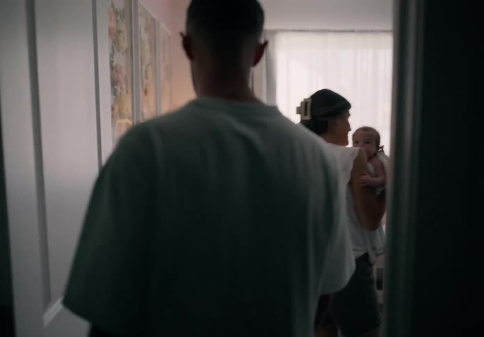 Mother with a baby in her arms and the father entering the room