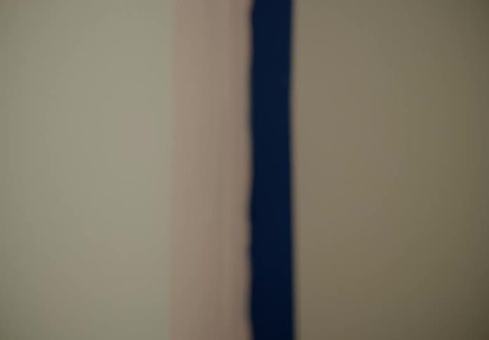 Hand holding a paintbrush and painting the wall of a room