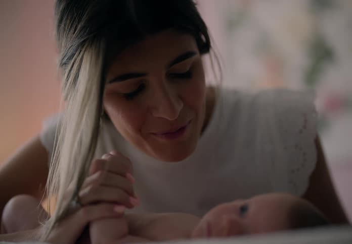 A mother playfully kissing her newborn son in the bedroom