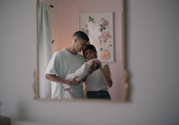 Mirror reflecting a father holding a baby next to the mother