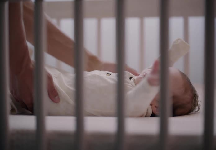 A man gently placing a baby inside a crib at home