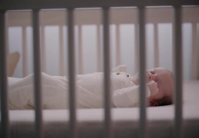 Person placing a sleeping baby in the crib