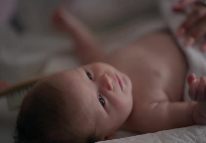Hand with a comb combing the hair of a newborn baby