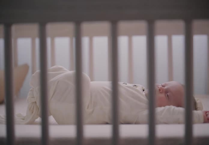 Hands placing a baby in the crib