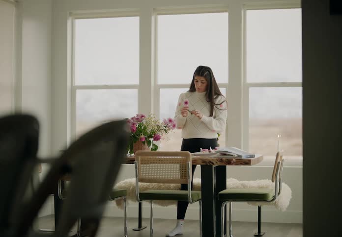 A woman is arranging flowers on the table