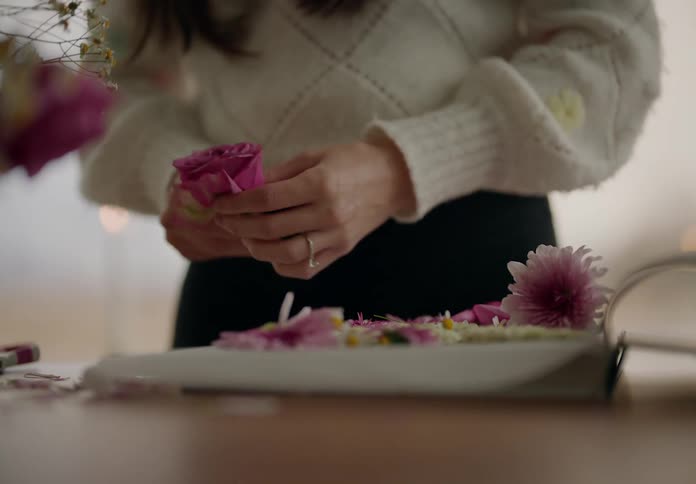 Woman arranges flowers on a plate on a table
