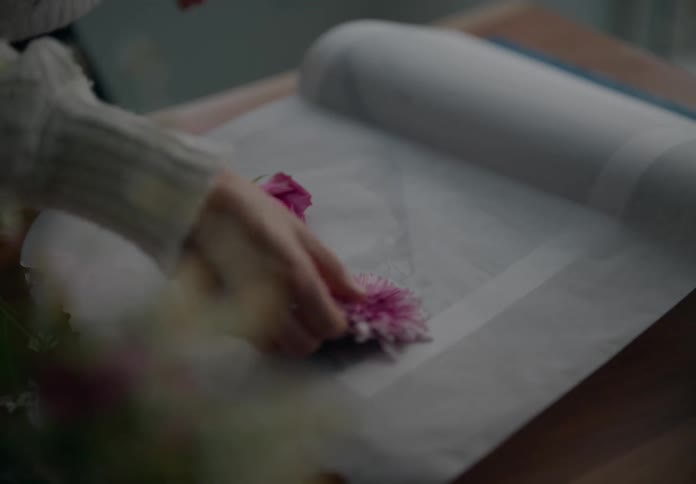 Close up of a woman setting flowers to dry over a cloth or paper