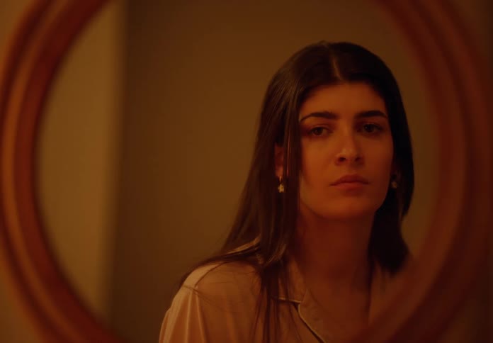 Woman poses in front of a round mirror