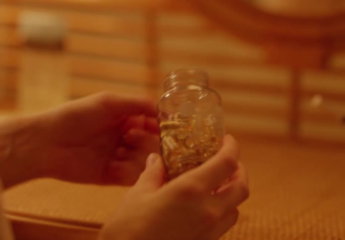 Hand opening a jar and taking out capsules