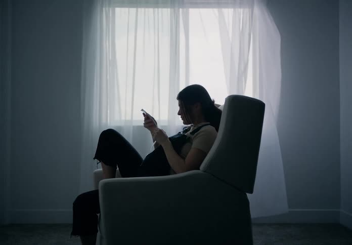 A pregnant woman sitting in a chair looking at photos
