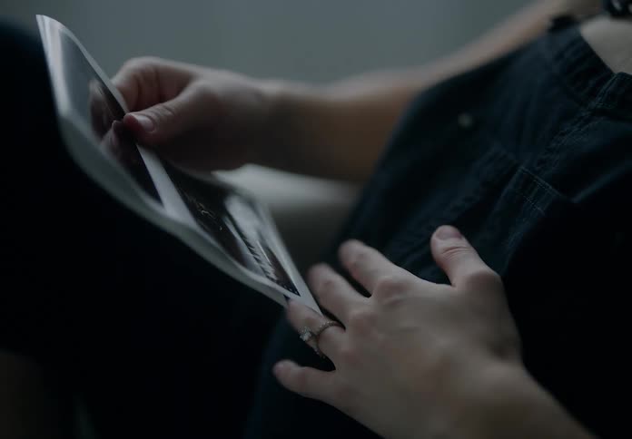 A pregnant woman sitting in a chair looking at echo sonograms