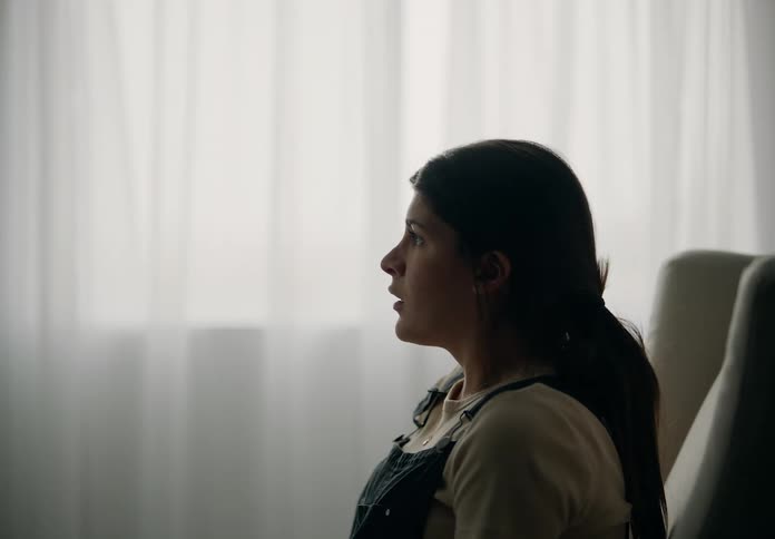 A woman sits in a couched seat sighs then looks towards the window