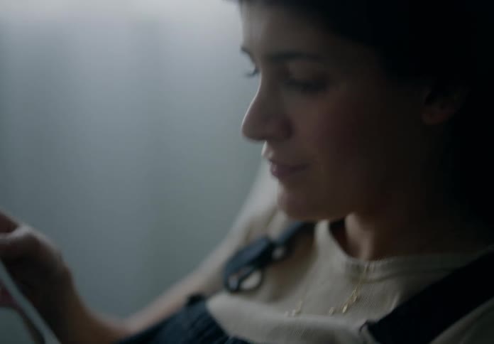 Pregnant woman placing hand on her belly and holding ultrasound photographs