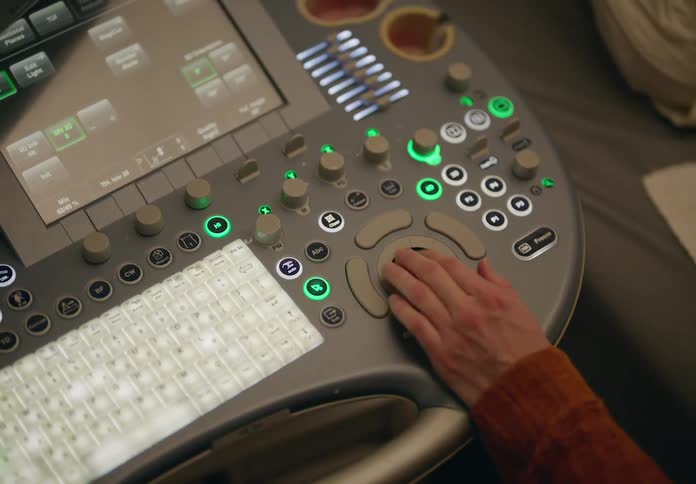 Person turns a dial on an ultrasound machine and views images on a screen