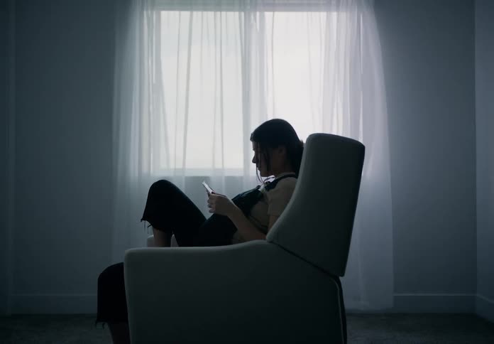 A pregnant woman sitting in a chair by a window with sheer curtains looking at echo sonograms