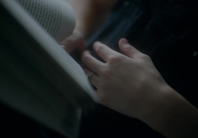 A pregnant woman sitting in a chair by a window reading a book