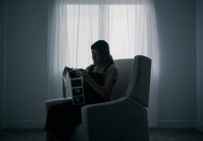 Pregnant woman sitting in an armchair taking pictures of an ultrasound