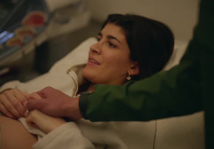 A pregnant woman lies down while a person performs an ultrasound on her belly