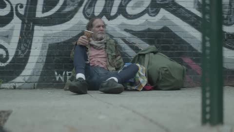 People walk by a homeless man on the street