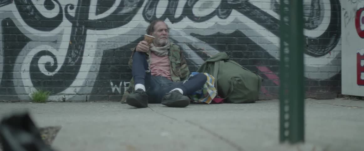 People walk by a homeless man on the street