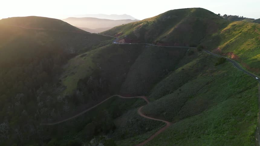 An aerial view of winding roads through a lush green mountain landscape