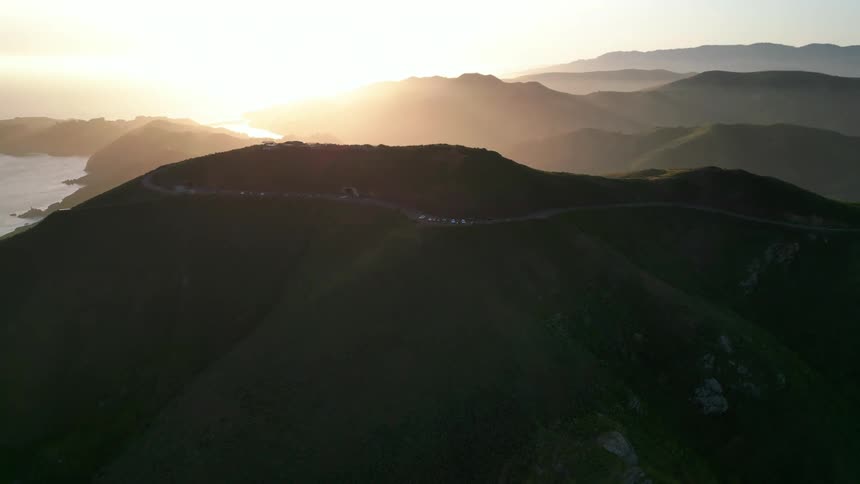 Aerial panorama of a mountain valley with the sun on the horizon