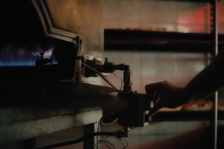 Hand adjusts a control on an industrial machine with flames visible