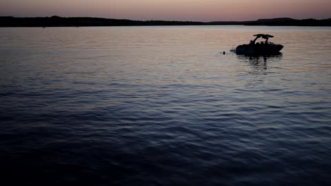People jumping from a boat on calm waters during twilight